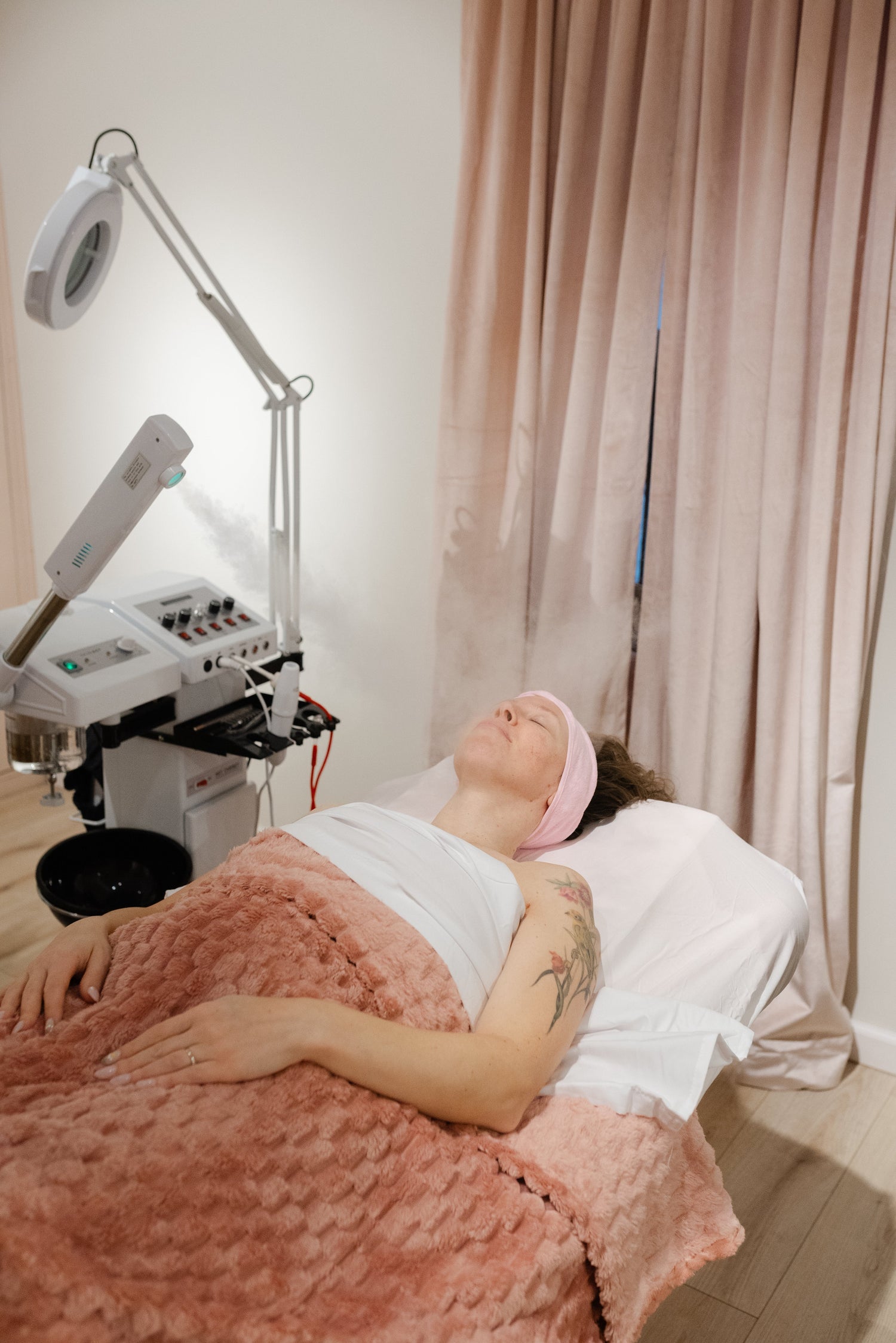 Woman receiving a facial treatment in a clinical setting with medical equipment.