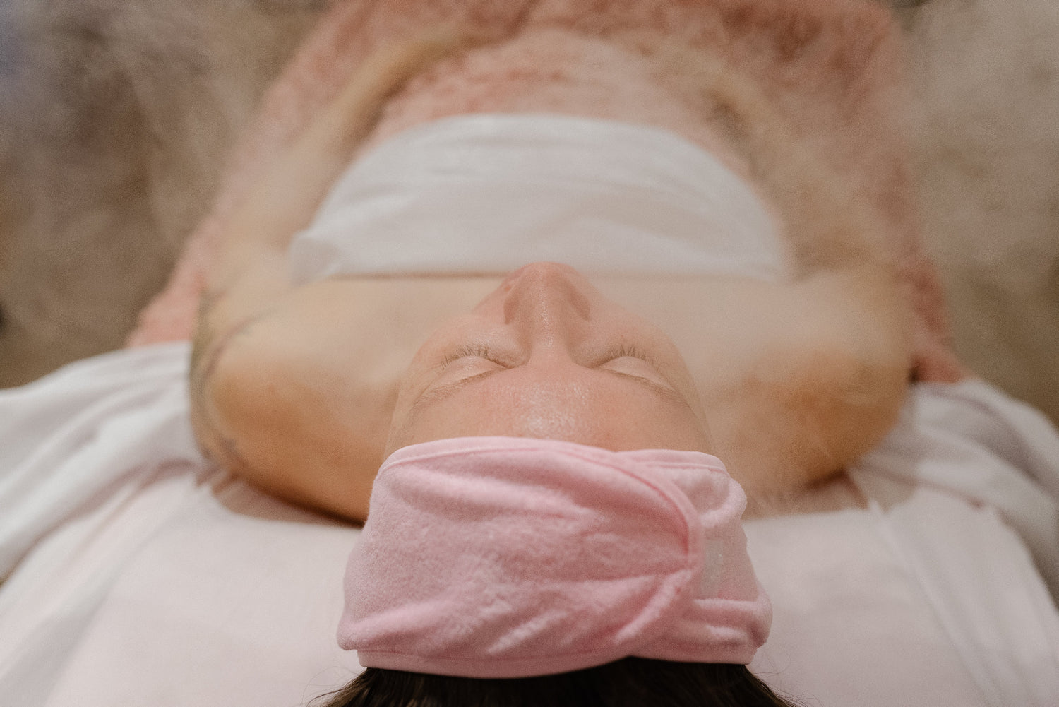 Person lying down with a pink eye mask on, eyes closed.