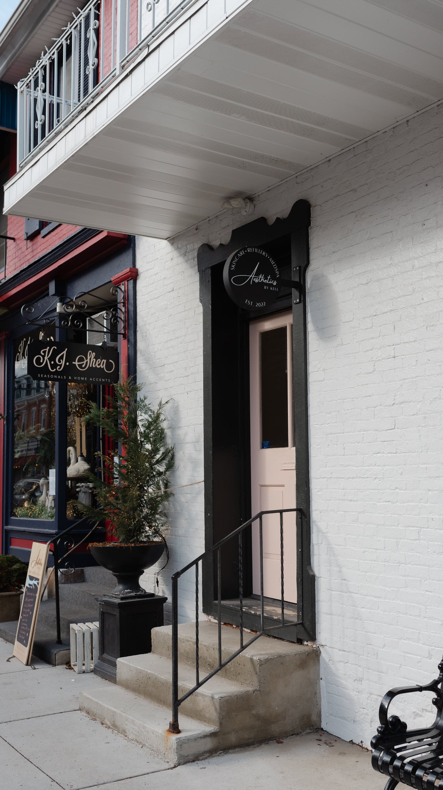 Storefront with a pink door and black sign on a white building